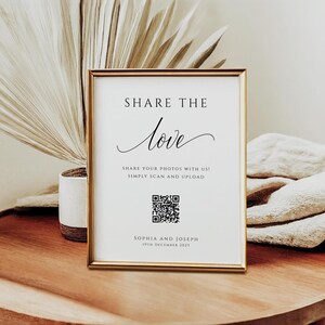 May include: A framed sign with the words "SHARE THE love" in elegant script. Below, it reads "SHARE YOUR PHOTOS WITH US! SIMPLY SCAN AND UPLOAD." Includes a QR code and the names "SOPHIA AND JOSEPH" with the date "19TH DECEMBER 2025". The frame is gold.