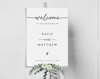 May include: A white wedding welcome sign with black calligraphy text that reads "Welcome to the wedding of Katie and Matthew, Saturday 12th July 2025".