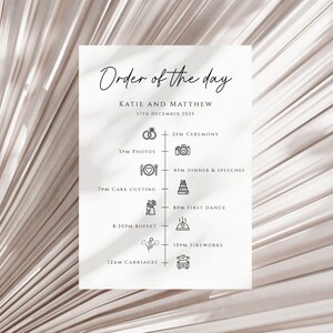 May include: A white wedding order of the day schedule with black text and icons. The schedule includes the ceremony, photos, cake cutting, dinner and speeches, first dance, buffet, fireworks, and carriages. The text reads "Order of the day", "Katie and Matthew", "17th December 2025", "2PM Ceremony", "3PM Photos", "4PM Dinner & Speeches", "7PM Cake Cutting", "8PM First Dance", "8:30PM Buffet", "10PM Fireworks", and "12AM Carriages".