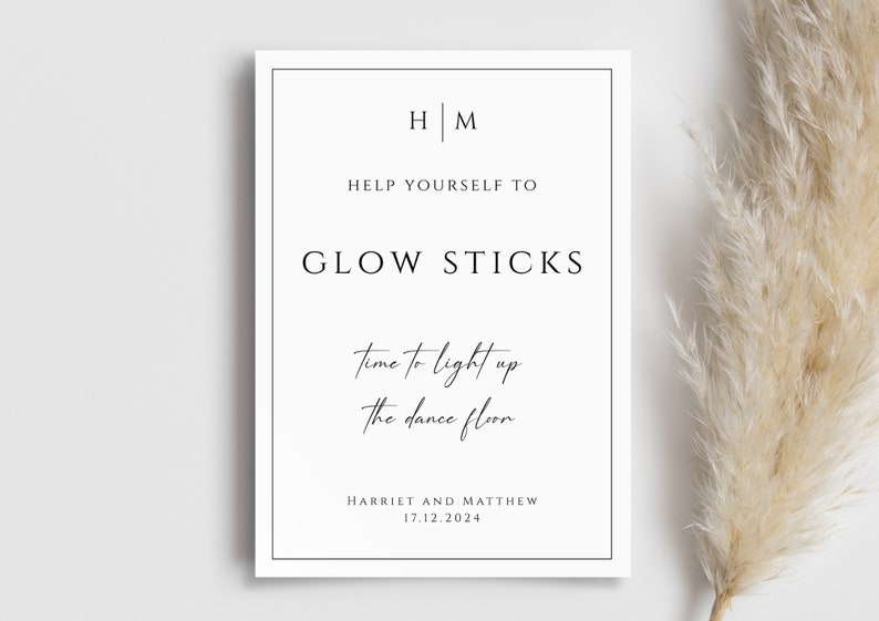 May include: A white sign with black text that reads "HM" and "Help yourself to Glow Sticks" with the tagline "Time to light up the dance floor". The sign also includes the names "Harriet and Matthew" and the date "17.12.2024".