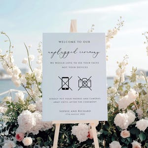 May include: A white sign on a wooden easel with the words "Welcome to our unplugged ceremony." The sign also includes the text "We would love to see your faces, not your devices." and the names Sophie and Richard.