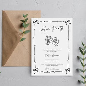 May include: A white invitation card with black text and illustrations for a "Hen Party" celebration. The card includes the bride's name, date, and location, along with a brown envelope and sprigs of greenery.