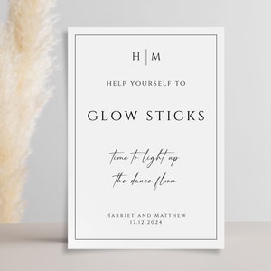 May include: A white sign with black text that reads "HM Help Yourself To Glow Sticks Time to light up the dance floor Harriet and Matthew 17.12.2024"