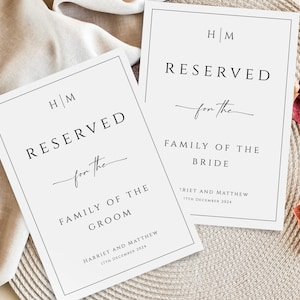 May include: Two white cards with black borders and text. The top card says "HM RESERVED for the FAMILY OF THE BRIDE" with the date "17TH DECEMBER 2024". The bottom card says "HM RESERVED for the FAMILY OF THE GROOM" with the date "17TH DECEMBER 2024".