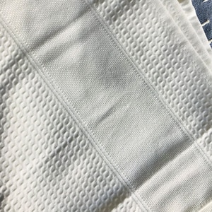 May include: White waffle weave bath towel with a textured pattern. The towel is folded in thirds.