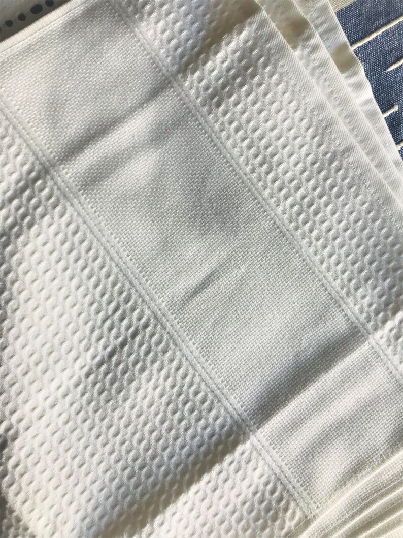 May include: White waffle weave bath towel with a textured pattern. The towel is folded in thirds.