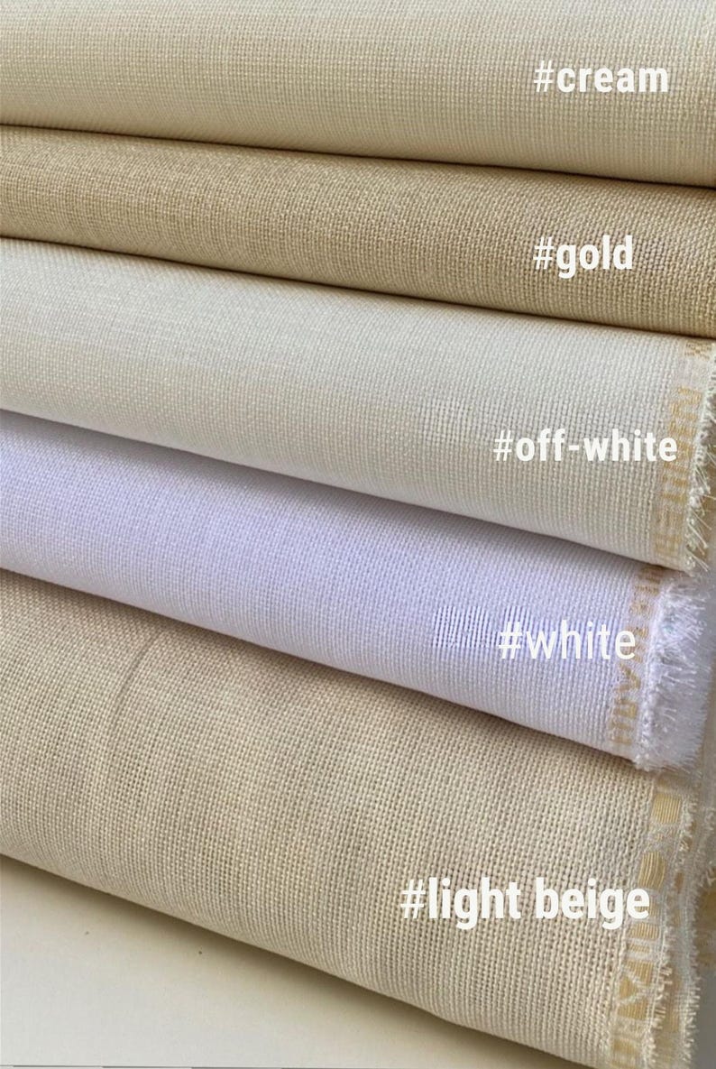May include: Close-up of folded fabric samples in cream, gold, off-white, white, and light beige. The fabric has a woven texture. The colors are labeled with hashtags: #cream, #gold, #off-white, #white, and #light beige.