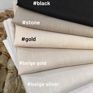 May include: A stack of fabric swatches in various neutral colors, including black, stone, gold, beige gold, beige silver, and silver. Each swatch has a corresponding color label. The fabrics appear to be textured.