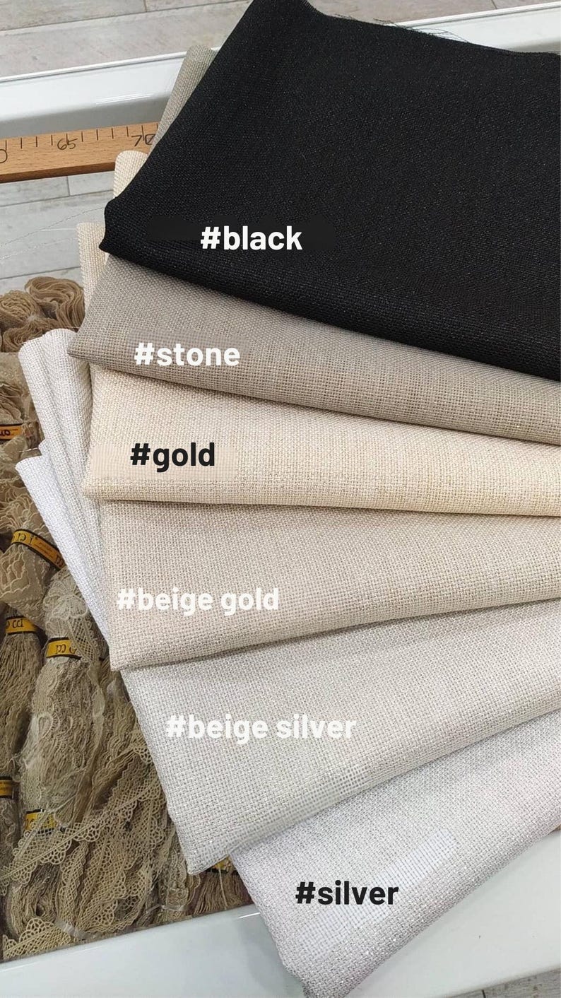 May include: A stack of fabric swatches in various neutral colors, including black, stone, gold, beige gold, beige silver, and silver. Each swatch has a corresponding color label. The fabrics appear to be textured.