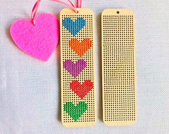 Peut inclure: Marque-page en bois avec des cœurs brodés en bleu, orange, violet, rouge et vert. Un cœur en feutre rose avec un ruban est également présent. Le marque-page comporte de petits trous pour la couture.