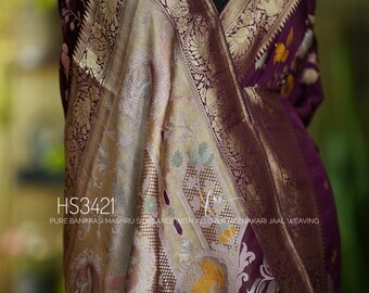 May include: A purple Banarasi Mashru silk saree with intricate gold and silver embroidery. The saree features a traditional design with floral motifs and a border with a paisley pattern. The saree is made with a fine weave and has a soft, luxurious feel. The saree is perfect for special occasions and festivals.