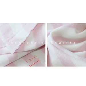 May include: Close-up of a soft, pink and white striped fabric. The fabric is folded and draped, showing the texture and pattern. The stripes are approximately 1.2 cm wide. The text "Brokenflower Gifts" is visible.