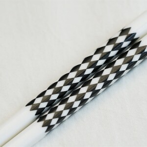 May include: A pair of white chopsticks with black and white diamond patterned accents.