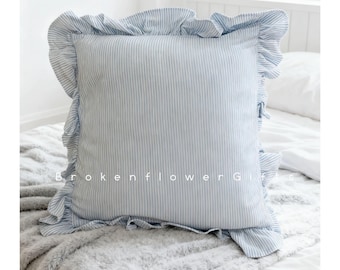 May include: A square pillow with a blue and white striped pattern and a ruffled edge. The pillow is on a bed with a gray blanket. The text "Brokenflower Gifts" is visible on the pillow.