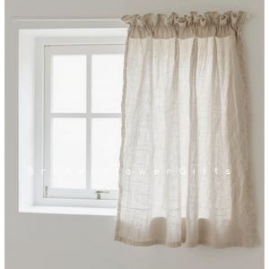 May include: A beige linen curtain hangs in front of a white window. The curtain has a ruffled top and a textured appearance. The window is divided into multiple panes, and the wall is white. The text "Brokenflower Gifts" is at the bottom.