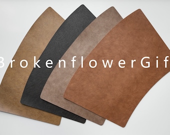 Könnte beinhalten: Fünf Leder-Platzsets in verschiedenen Farben: Braun, Dunkelbraun, Grau, Schwarz und Hellbraun. Die Platzsets sind fächerförmig angeordnet. Der Text "BrokenflowerGift" ist im Bild sichtbar.