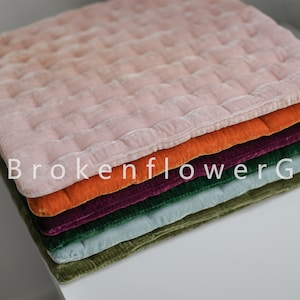 以下が含まれることがあります： ピンク、オレンジ、ボルドー、グリーン、ライトブルーなど、さまざまな色のキルティングされたクッションカバーが6枚重ねられています。一番上のクッションカバーはピンクで、キルティングされたパターンがあります。スタックの一番下に「BrokenflowerGift」というテキストが表示されています。