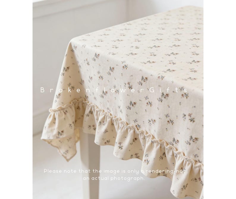 May include: Cream-colored tablecloth with a delicate floral pattern and ruffled edges. The fabric is adorned with small, scattered flowers in shades of brown and gray. The text "Brokenflower Gifts" is visible on the tablecloth.
