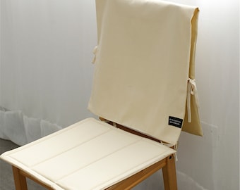 Puede incluir: Un cojín de silla de color crema con un cojín de respaldo a juego. El cojín tiene un diseño acolchado y el cojín de respaldo tiene una etiqueta que dice "It's Easy to Decorate".