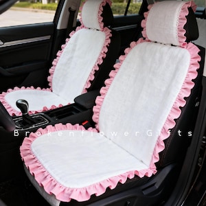 May include: White car seat covers with pink ruffled edges. The covers include headrest covers and seat covers. The text "BrokenFlowerGifts" is visible on the image.