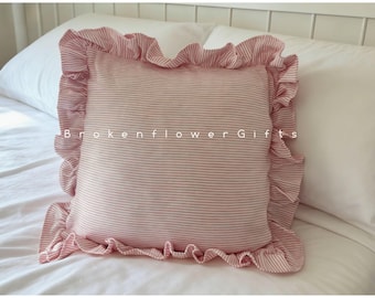May include: A square pillow with a pink and white striped pattern and a ruffled edge. The pillow is on a white bed with the text "Brokenflower Gifts" printed on the front.