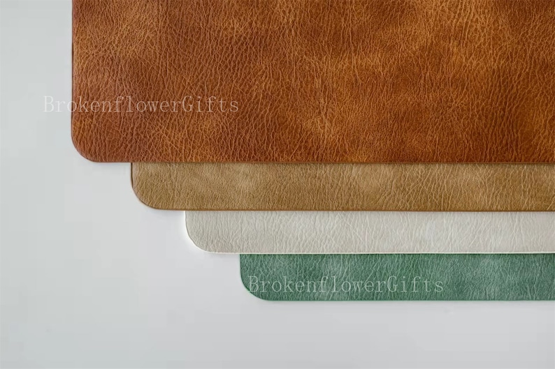 Może przedstawiać: Cztery sk&oacute;rzane podkładki pod talerze w r&oacute;żnych kolorach: brązowym, beżowym, białym i zielonym. Podkładki są ułożone jedna na drugiej.