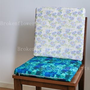 May include: A wooden chair with a blue and green floral patterned cushion and a white cushion with a blue floral pattern on the back.
