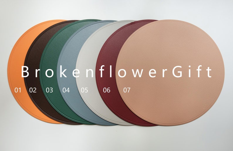 May include: Seven round leather placemats in different colors: orange, brown, green, blue, gray, burgundy, and peach. The placemats are arranged in a row with the text "BrokenflowerGift" and numbers 01-07 printed below.