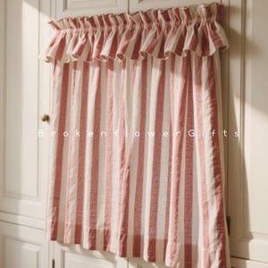 Può includere: Una tenda a righe rosse e bianche con una mantovana a balze è appesa davanti a un armadio bianco. La tenda presenta strisce verticali e la mantovana ha un bordo a balze. Il testo "Brokenflower Gifts" è stampato sulla tenda.