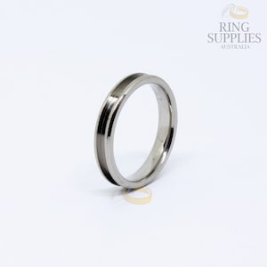 May include: A silver wedding band with a grooved edge.