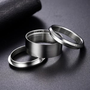 May include: Three silver metal rings of different sizes and styles. The rings are stacked on top of each other.