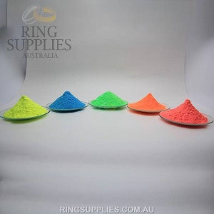 May include: Five small glass plates each hold a vibrant mound of colored powder: neon yellow, blue, green, orange, and red-orange. The image has the text "RING SUPPLIES AUSTRALIA" and "RINGSUPPLIES.COM.AU".