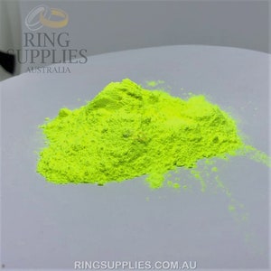 May include: A pile of bright neon yellow powder sits on a white surface. The powder is finely ground and has a slightly textured appearance. The image includes the text "RING SUPPLIES AUSTRALIA" and "RINGSUPPLIES.COM.AU".