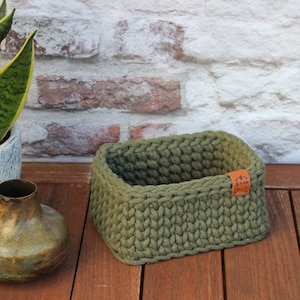 Peut inclure: Un panier de rangement en crochet vert avec une étiquette en cuir marron qui dit "The Little Things".