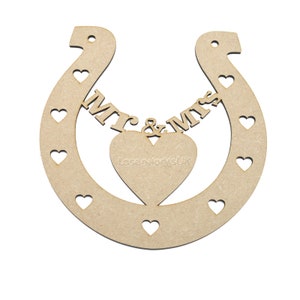 May include: A wooden horseshoe with the words "Mr & Mrs" and a heart cutout in the center. The horseshoe is decorated with small heart cutouts around the edges.