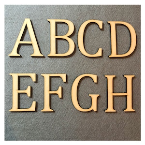 May include: Wooden letters in a serif font, spelling out the letters A B C D E F G H. The letters are a light brown color and are arranged in two rows.