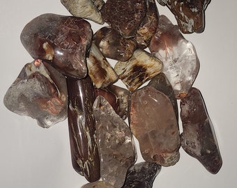 May include: A collection of tumbled stones in shades of brown, white, and clear. The stones have a variety of shapes and sizes, and some have a translucent quality.