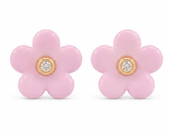 Puede incluir: Un par de pendientes de botón con forma de flor de cinco pétalos. Cada pendiente presenta un acabado de esmalte rosa claro liso con una pequeña piedra preciosa redonda y transparente engastada en un centro circular dorado.