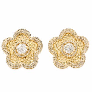 May include: A pair of gold flower-shaped stud earrings featuring a central round clear stone surrounded by a textured lattice pattern and an outer border encrusted with numerous small, sparkling clear stones along the five rounded petals.