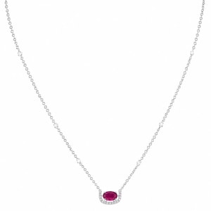 Könnte beinhalten: Zarte Silberkette mit einem ovalen Rubinanhänger, umgeben von kleinen, funkelnden Diamanten. Die Kette ist mit gleichmäßig verteilten, kleinen Diamanten besetzt. Die Halskette wird vor weißem Hintergrund präsentiert.