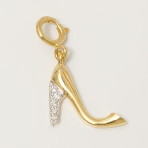 May include: A gold-coloured high-heeled shoe charm with a white, gem-studded heel. The charm has a clasp for easy attachment to a bracelet or necklace. The shoe charm is a classic accessory.