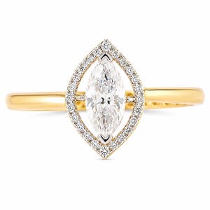 May include: A yellow gold ring featuring a central marquise-cut diamond surrounded by a marquise-shaped halo of small round pavé-set diamonds. The band is smooth and polished, providing a clean contrast to the intricate diamond-encrusted setting.