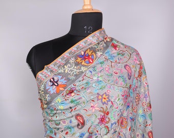 May include: A gray shawl with a floral pattern in shades of pink, blue, green, and yellow. The shawl is draped over a mannequin.