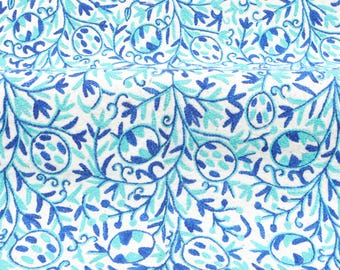 May include: White fabric with a blue and turquoise floral pattern. The pattern features stylized leaves and flowers with a repeating design.