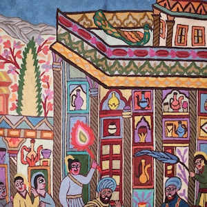 May include: A colorful embroidered tapestry depicting a scene with a peacock on a rooftop, people in traditional clothing, and a building with intricate details. The tapestry is made with wool and features a variety of colors, including red, blue, green, yellow, and orange.