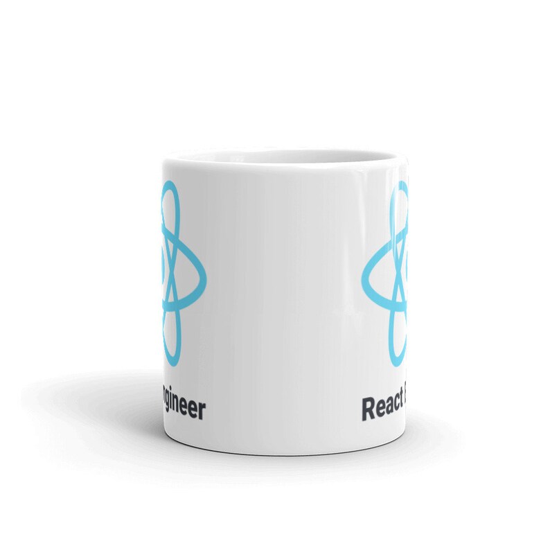 May include: White ceramic mug featuring a light blue atom symbol and the words "React Engineer". The mug is cylindrical with a handle. The mug is suitable for hot or cold beverages.