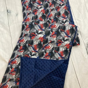 May include: A blue and white reversible blanket with a Spiderman pattern on one side and a soft, blue minky fabric on the other side.