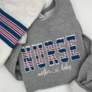 May include: Gray sweatshirt with the word "NURSE" in red, white, and blue stripes. The text "mother ♥ baby" is written below the word "NURSE".