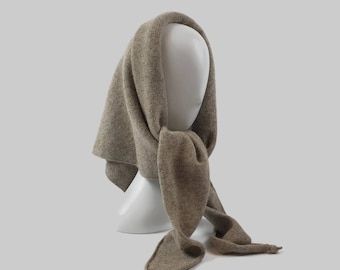 May include: A brown knitted scarf with a long, flowing design. The scarf is draped over a mannequin's head and neck.