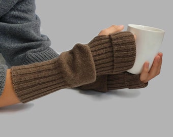 May include: Brown knitted fingerless gloves with a ribbed texture. The gloves are folded back at the wrist.